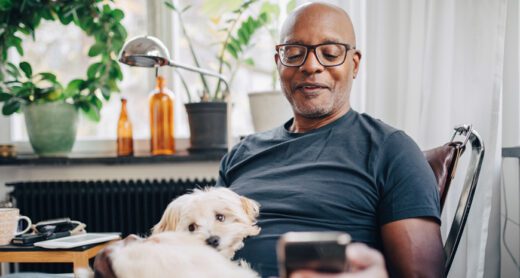 Man reading phone with dog in his lap