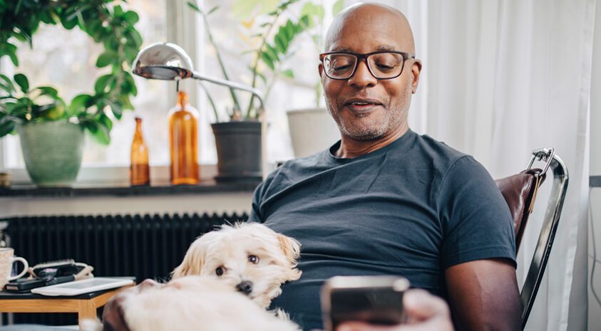 Man reading phone with dog in his lap