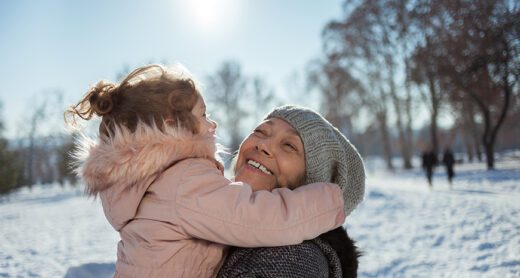 Woman hugging child outside in winter