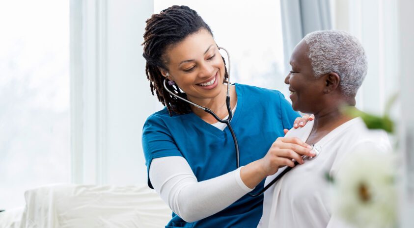 Woman doctor with patient checking her heartbeat