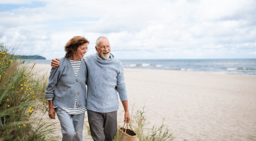 Retired couple walking on beach together