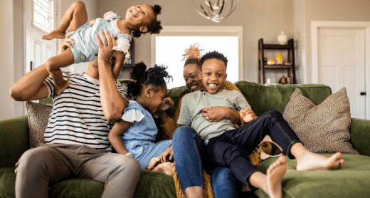 Young family laughing on couch in their home