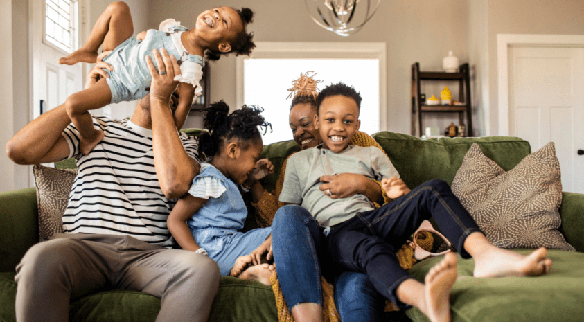 Young family laughing on couch in their home