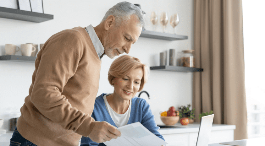 Retiring couple reviewing medical bills at computer