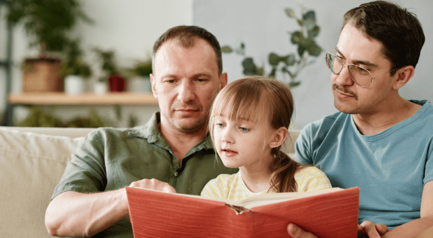 Fathers reading book to their daughter