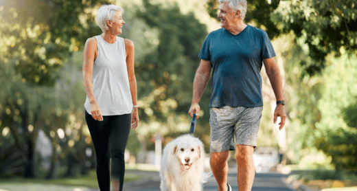 Retired couple smiling on a walk with their dog