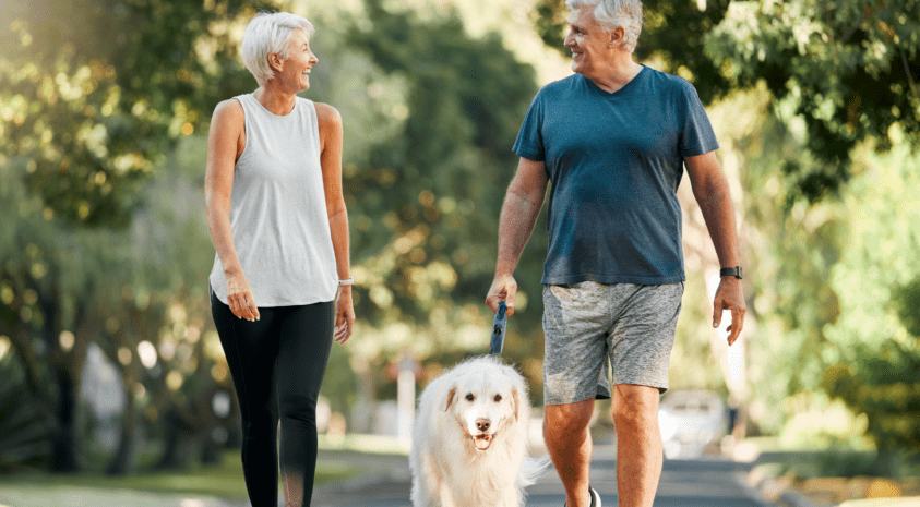 Retired couple smiling on a walk with their dog