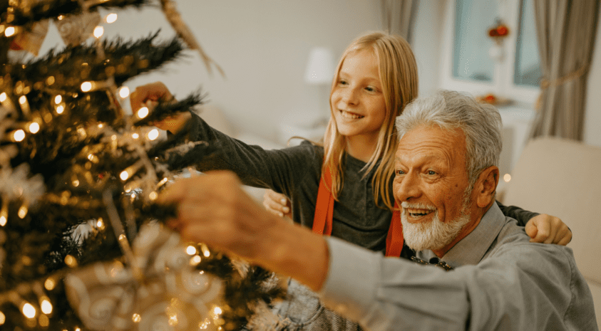 Senior decorating Christmas tree with granddaughter