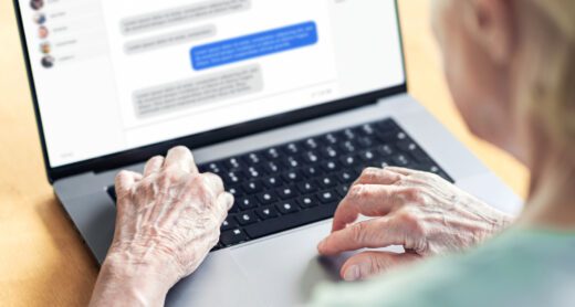 Older woman looking at a laptop as her hands are on the keyboard.