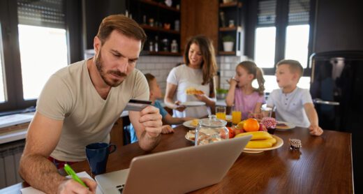 Man going through bills with family behind him.