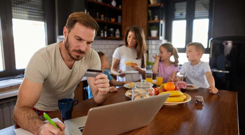 Man going through bills with family behind him.