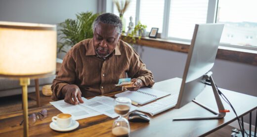 A senior adult man sitting at a desk doing work.