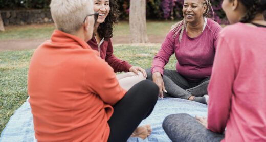 Multigenerational group of women on a picnic blanket socializing and smiling.