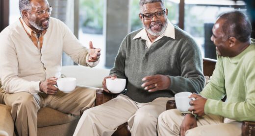 Three mature African-American men sitting in a coffee shop drinking coffee.