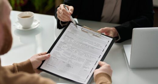 Close up of two people's hands holding an insurance form on a clipboard.