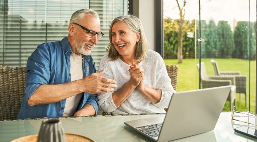 An older couple looks at a laptop.