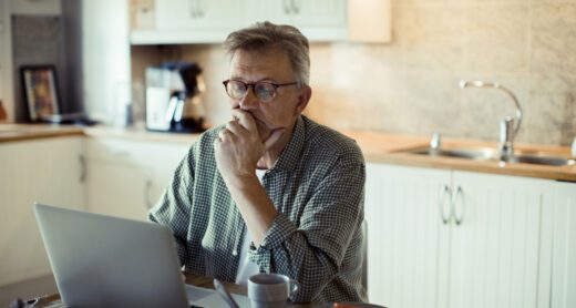 Close up of a mature man using a laptop at home looking concerned.