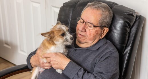 Senior man relaxing at home in a recliner chair with his adopted shelter dog.