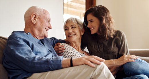 Three generations on a couch looking at each other and smiling.