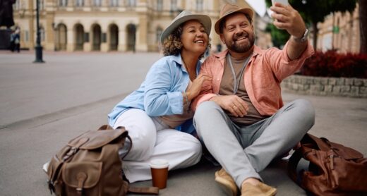 A couple takes a selfie while sitting on the ground.