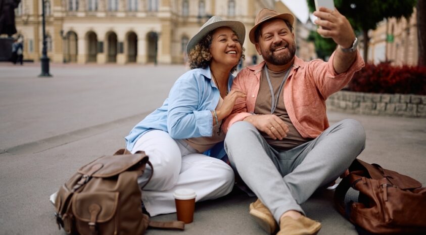 A couple takes a selfie while sitting on the ground.