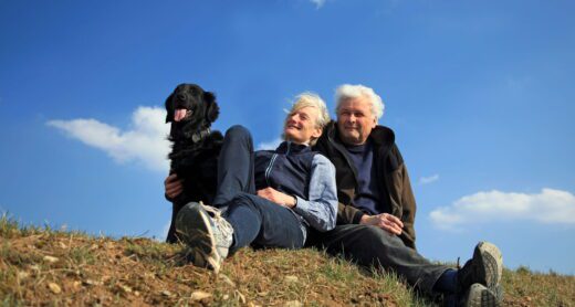 Happy elderly couple enjoying nature with their dog