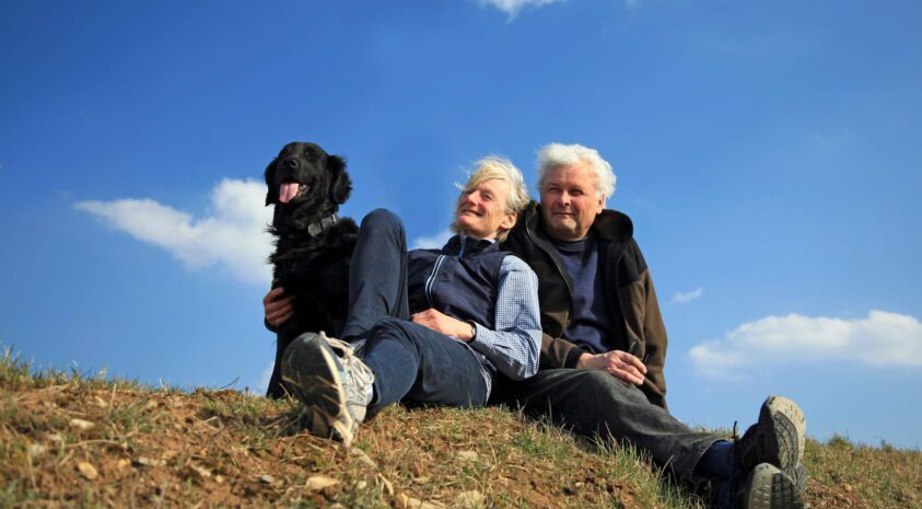 Happy elderly couple enjoying nature with their dog