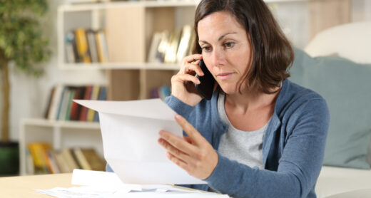 A woman talks on the phone while reviewing documents.