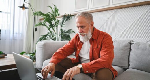 Senior man working on laptop looking concerned.