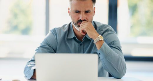 Thoughtful businessman working on laptop in the office.