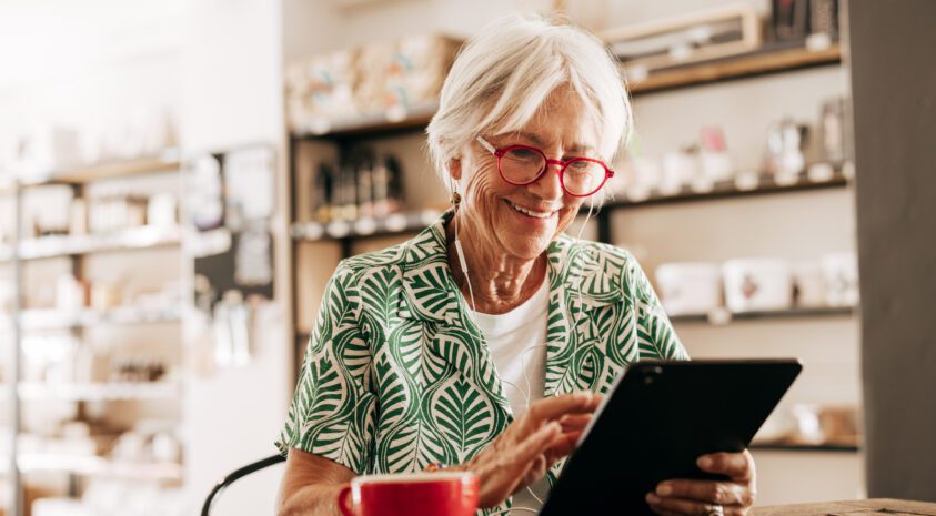 Older woman holding a tablet.