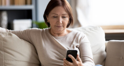 Worried person on couch, looking at phone.