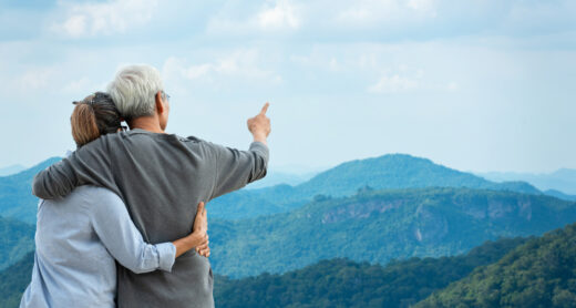 A senior couple pointing to a mountain.