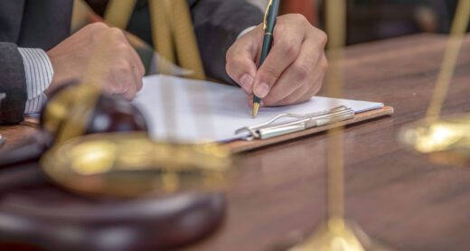 Close up of lawyer's hands signing papers in a courtroom setting.