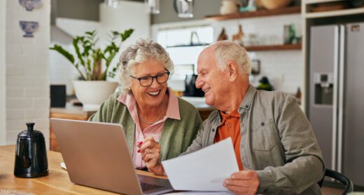 Happy retired couple works on their taxes at their kitchen table.