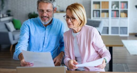 A retired couple works on their taxes and reviews tax documents in their kitchen.