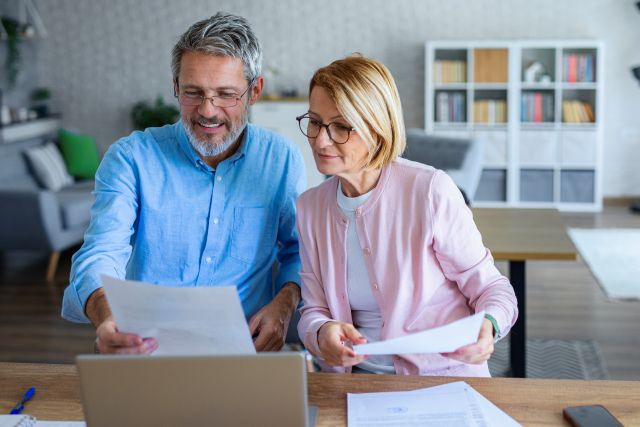 A retired couple works on their taxes and reviews tax documents in their kitchen.