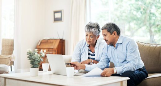 A retired couple reviews fixed annuity versus variable annuity options over coffee at home