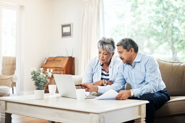A retired couple reviews fixed annuity versus variable annuity options over coffee at home