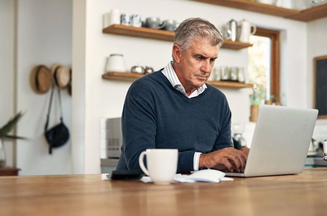 A senior man work on his laptop at home