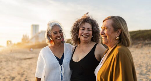 Retired women friends talk and enjoy time on the beach.