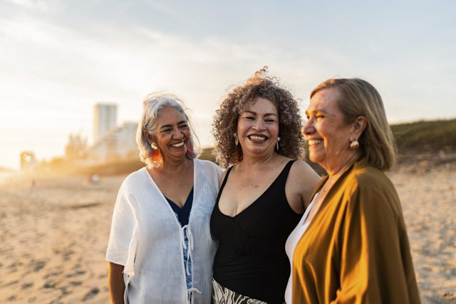 Retired women friends talk and enjoy time on the beach.