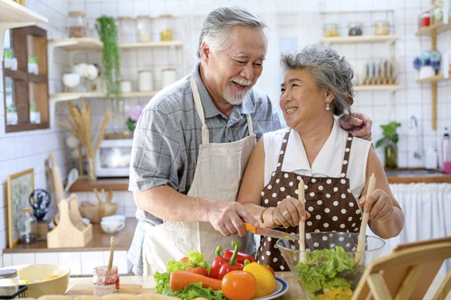 Happy senior couple cooks at home.