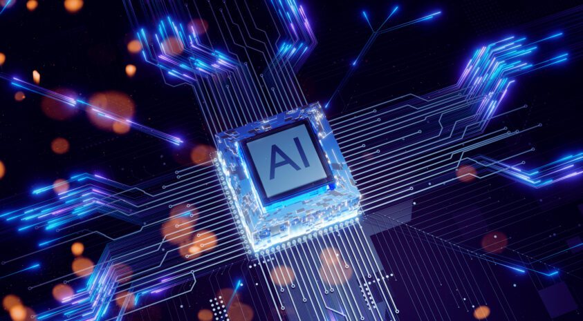 Computer chip labeled "AI" on a circuit board. The scene is illuminated with a cool blue glow.