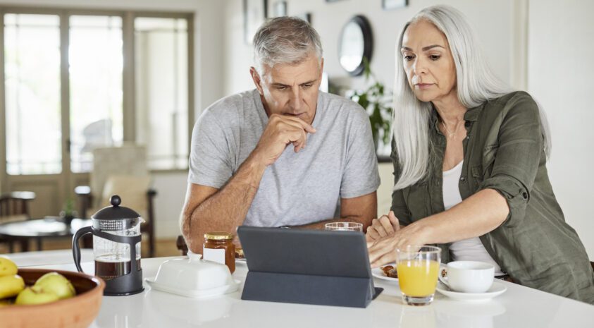 Retirement age couple looking concerned at a laptop.