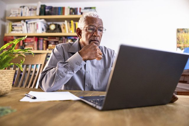 A senior man reviews Medicare coverage on his laptop at home